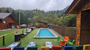 an outdoor swimming pool with chairs and a house at Cămăruța din Apuseni in Valea Ierii