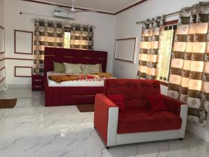 a bedroom with a bed and a red couch at Alberjah Hotel in Atimpoko