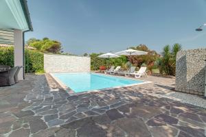 a pool with chairs and umbrellas next to a house at Belvedere in Isola Albarella