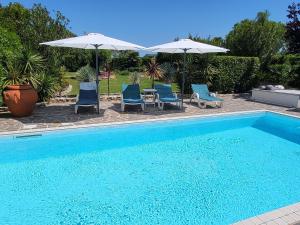 a swimming pool with blue chairs and umbrellas at Belvedere in Isola Albarella +42 photos