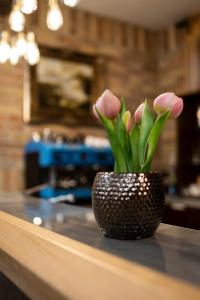 a vase filled with pink flowers sitting on a counter at Fenyves fogadó in Ásotthalom