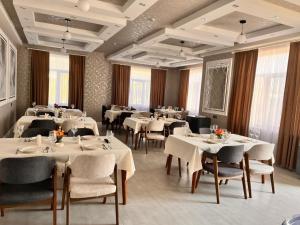 a restaurant with white tables and chairs and windows at River Hotel Restaurant in Quba
