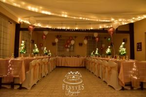 a row of tables in a banquet hall with lights at Fenyves fogadó in Ásotthalom