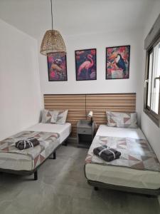 two beds in a room with paintings on the wall at Lassa Holiday Apartament in Torrevieja