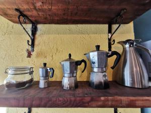 three tea kettles sitting on a wooden shelf at Adagio Guesthouse in Caprie