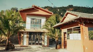 a house with palm trees in front of it at Homestay Minano in Mock Den