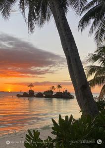 a sunset on a beach with palm trees and the ocean at Isla Haus Boracay in Boracay