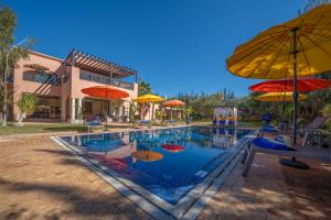 a swimming pool with umbrellas and chairs and a swimming pool at Villa JUZYAN une parenthèse de bien-être et de convivialité in Marrakesh