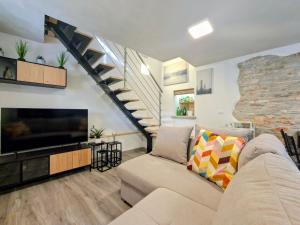 a living room with a couch and a tv and a staircase at Apartments Casa Sossa in Vilanija