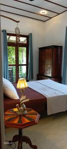 a bedroom with a bed and a table with a lamp at Wooden hostel in Weligama