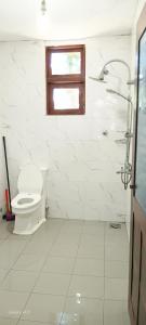 a white bathroom with a toilet and a shower at Wooden hostel in Weligama