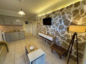 a living room with a stone wall with a tv at Alkionis Garden View Apartments in Lefkada