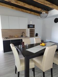 a kitchen with a black table and white chairs at Stan na dan BOVKA in Široki Brijeg