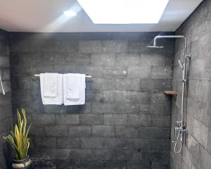 a bathroom with white towels hanging on a brick wall at The Hills Penida in Nusa Penida