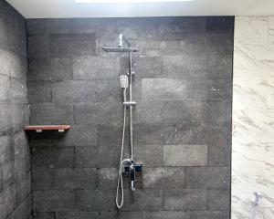 a shower in a bathroom with a stone wall at The Hills Penida in Nusa Penida