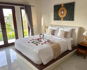 a bedroom with a large white bed with flowers on it at The Hills Penida in Nusa Penida
