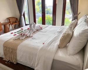 a white bed with flowers on it with a window at The Hills Penida in Nusa Penida