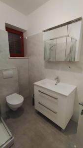 a bathroom with a white sink and a toilet at Apartment Lovor in Krk +17 photos