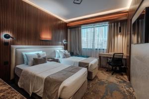 a hotel room with two beds and a desk at Kuwait Continental Hotel in Kuwait