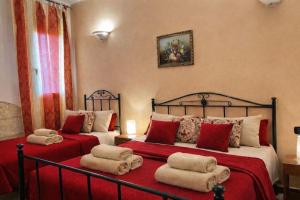two beds in a bedroom with red sheets and pillows at Agriturismo Residence Molle con piscina in Carpignano Salentino