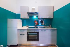 a kitchen with a white refrigerator and green walls at Casa Bratz in Marciana Marina +2 photos