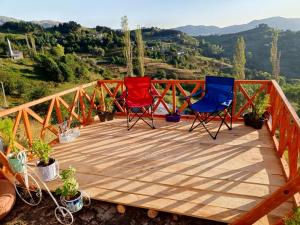 three chairs sitting on a wooden deck with a view at Balcı Konukevi in Artvin