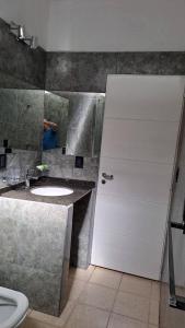 a bathroom with a white door and a sink at Bosquesito in Mina Clavero