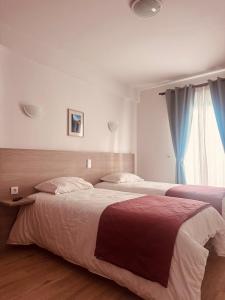 a bedroom with two beds and a window at Residencial Santo António in Santa Cruz