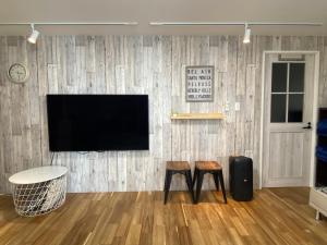 a living room with two stools and a television on a wall at プチリゾート・ひじきwest in Hijiki