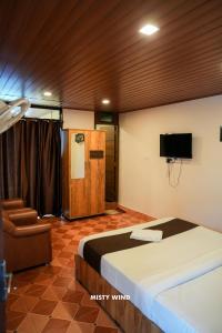 a bedroom with a bed and a tv and a chair at Vythiri Misty Wind Holiday Homes in Vythiri