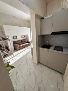 a kitchen with white cabinets and a couch in the background at Chez Grenuel in Sanremo