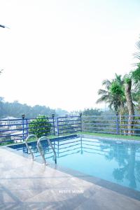 a swimming pool with a fence and trees in the background at Vythiri Misty Wind Holiday Homes in Vythiri +6 photos