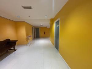 an empty hallway with a yellow wall and a piano at Hotel O Peneka Inn in Kota Bharu