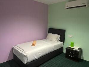 a bedroom with a bed and a nightstand with a wooden object on it at Hotel O Peneka Inn in Kota Bharu
