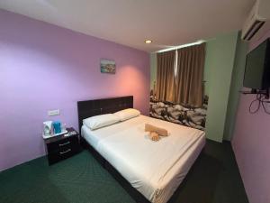 a bedroom with a bed with a teddy bear on it at Hotel O Peneka Inn in Kota Bharu