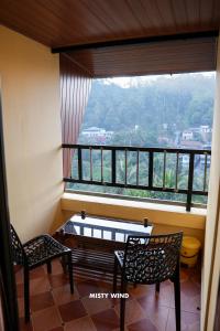 a balcony with two chairs and a table and a window at Vythiri Misty Wind Holiday Homes in Vythiri