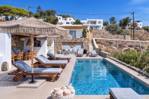 a villa with a swimming pool and a house at Trinity Mykonos - Beachfront Villa in Platis Gialos