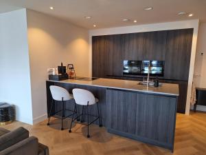 a kitchen with a bar with two stools at Bij de Haven op Urk in Urk +36 photos