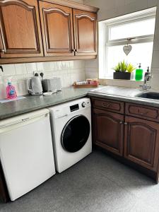 a kitchen with a white dishwasher and a sink at Goosemoor Cottage in Longdon