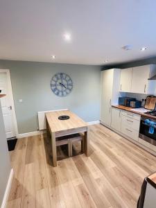 a kitchen with a wooden table and a clock on the wall at Barber House, Hoyland with two allocated parking spaces in Hoyland Nether
