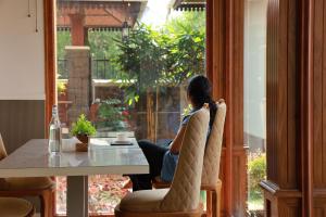 a woman sitting at a table looking out a window at Adonna Beach Resort in Alleppey