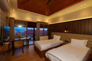 a bedroom with two beds and a desk and a television at Adonna Beach Resort in Alleppey +124 photos