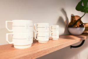three white cups sitting on a wooden shelf at Cà Bèla - Venini in Milan