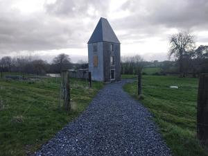 a small building in a field with a gravel road at La Tour de Vesly in Belval