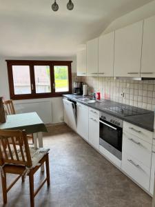 a kitchen with white cabinets and a table and a chair at Albbruck, Feriendomizil Albsteig in Albbruck