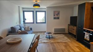 ein Wohnzimmer mit einem Tisch, einer Couch und einem Fernseher in der Unterkunft Le duplex in Les Angles