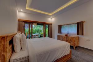 a bedroom with a large bed and a window at Ratih Guest House in Ubud