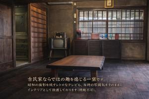 a room with a table and a tv in it at ゲストハウス　竹亭 in Marugame