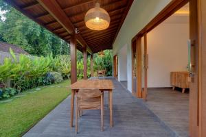 an outdoor patio with a wooden table and chairs at Ratih Guest House in Ubud
