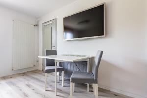 a white table with chairs and a tv on a wall at Immensee Appartments by Mainka Properties in Immensee